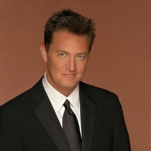 A headshot of a man (Matthew Perry) wearing a coat and tie.