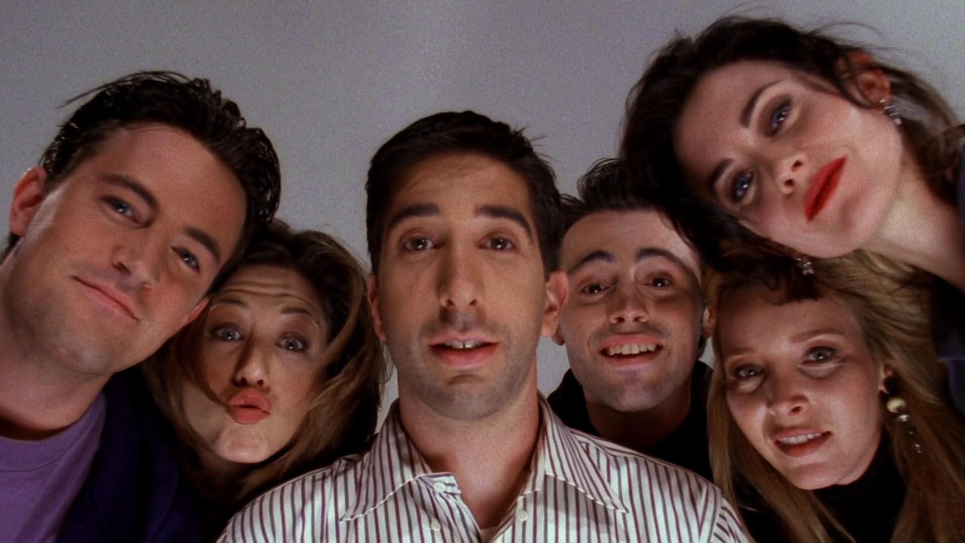 The cast of 'Friends' all leaning over and looking down at the camera.