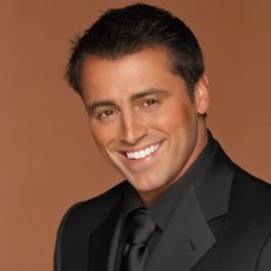 A headshot of a man (Matt LeBlanc) wearing a black coat and tie.